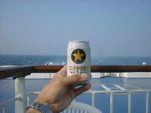 海に向かって缶ビールで乾杯している写真