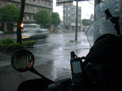土砂降りの街角で雨宿りをしているバイクの写真
