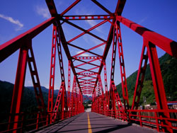 高知にて青空に掛かる真紅の鉄橋をわたっている写真
