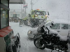 2008年元旦に富磯のセイコーマートで休憩している雪を被ったバイクと燃料を入れている除雪車の写真