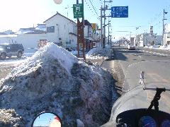 除雪された雪が路肩に高く積まれている道路の写真