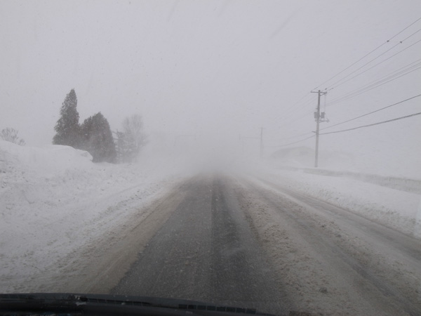 視程不良の吹雪きの中を車で走っている写真
