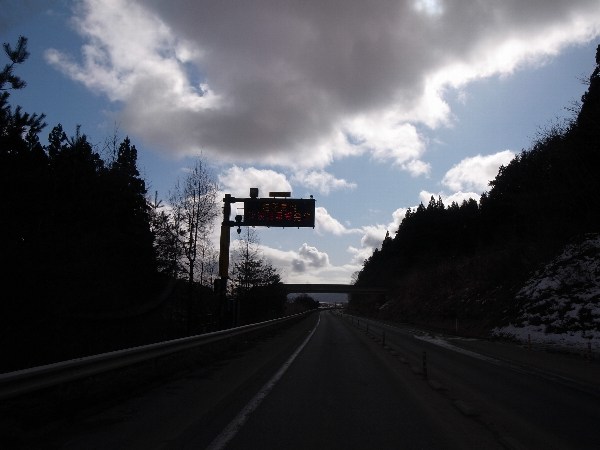 道路上に設置された電光掲示板に津波注意報発令中の文字が表示されている写真