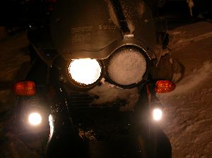 夜中に吹雪の中を走ってきてライトに雪がついてしまったバイクの写真