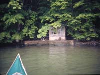 湖畔にたたずむ掘っ立て小屋風の簡易温泉施設の写真