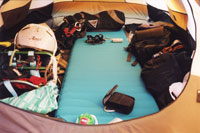 テントマットを敷いている散らかったテントの中の写真