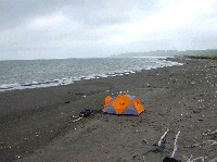 遠く伸びる砂浜にぽつんと張ったカラフルなオレンジ色のテントの写真