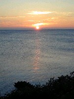 波の無い静かな海面に沈む夕日の写真