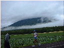 雲の中に半分隠れている後志山をバックに走るランナーの写真