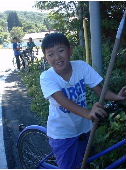 川で魚を突くための「やす」を持って自転車で秘密の場所に向かう途中の少年の写真