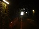 レンガ作りの凸凹なトンネルの壁に出口から明るい光が差し込んでいる写真