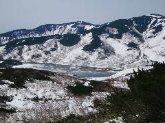 まだ雪に覆われている羅臼湖と雪解けの進む知西別岳(ちにしべつたけ)の写真