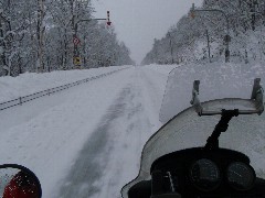 緩み始めた圧雪道路をバイクで走っている写真