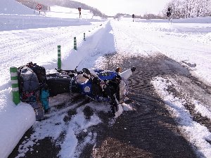 雪道で転倒しているバイクの写真