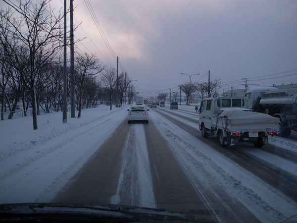 おおきく車間距離をとって凍結路面を走行している車の写真