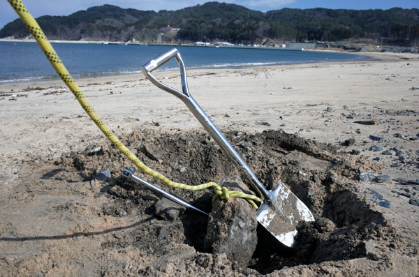 吉里吉里海岸に埋まるコンクリート片を掘り出す写真