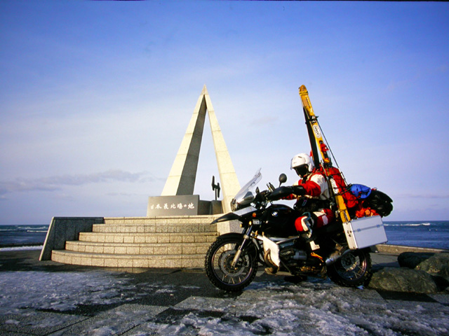 2007年元日の宗谷岬で日本最北端の碑の前で記念撮影をするスキー搬送状態のバイクの写真