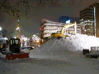建設中の雪祭り大雪像の基礎工事の写真、ショベルカーで雪を積み上げています