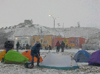 横殴りの吹雪の中で宗谷岬の広場に張られたバイクツーリストのテント群の写真