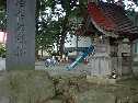 道端の神社の境内にあった道祖神の石碑の奥で遊ぶ子供達の写真