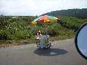 でかいビーチパラソルの下、アイスクリームを売るババヘラアイスの売り子のばさまの写真