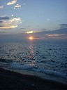 夕焼け色に染まった太陽が琵琶湖に解けていく写真