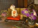 赤い座布団に座ってお客に挨拶しているかわいい日本人形のオブジェの写真