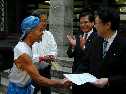 厚生大臣に直接面会して要望書を手渡し、大臣と握手する澤本さんのしゃしんです。